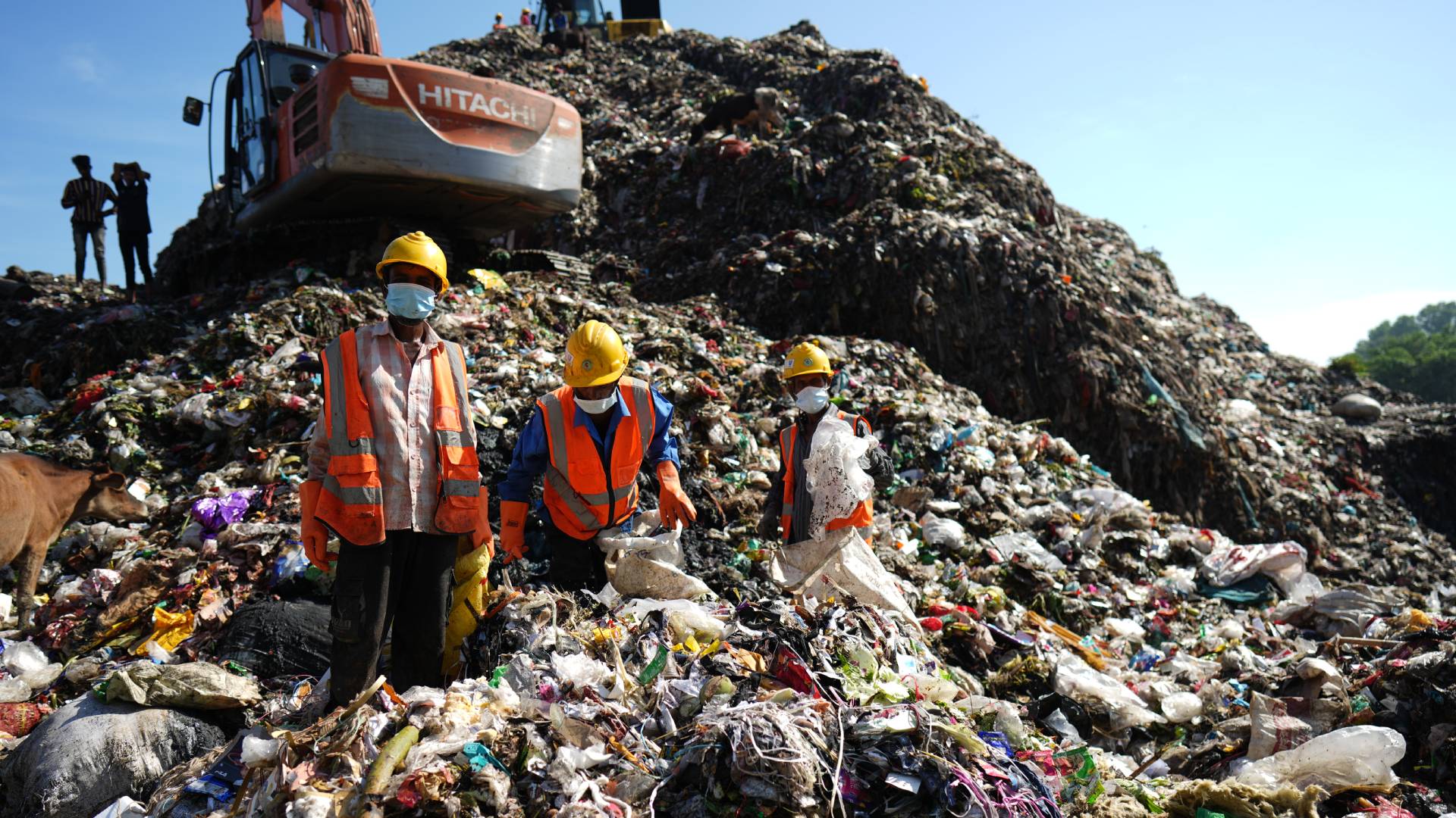 Three waste workers are working in the landfill